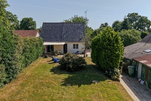 A residential property with a sloped roof, a covered patio, and a well-maintained lawn.