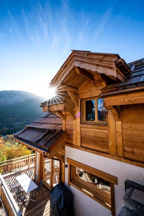 Eine Holzchalet mit Balkon, einem Essbereich und Blick auf die Berge.