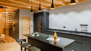 Eine moderne Küche mit einer zentralen Kochinsel, schwarzen Schränken und Holzbalken an der Decke.