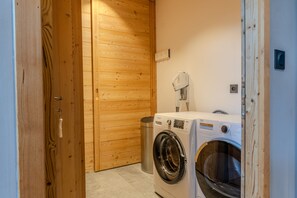 Ein Waschraum mit Waschmaschine, Trockner und einer Holztür.