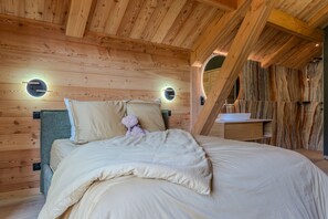 Ein Schlafzimmer in einer Holzhütte mit einem Bett, Kissen, einem Teddybären und einem Nachttisch.