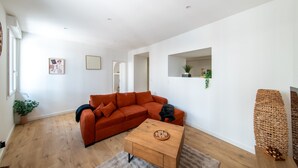A modern living room with a sectional sofa, a wooden coffee table, and a small plant on the windowsill. - Le Cocon du Centre - Appt au cœur de Poitiers (Poitiers)