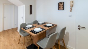 A dining area with a wooden table set for four, grey chairs, a black rug, and a 'WELCOME' sign on the wall. - Le Cocon du Centre - Appt au cœur de Poitiers (Poitiers)