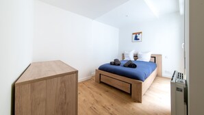 A bedroom with a wooden bed, a small wooden desk, and a white wall with a framed picture. - Le Cocon du Centre - Appt au cœur de Poitiers (Poitiers)