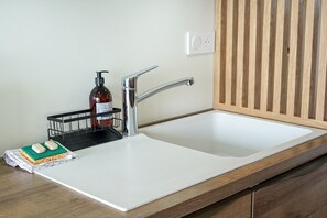Eine Küche mit weißem Spülbecken, Holzauskład und einer Seifenspenderflasche.