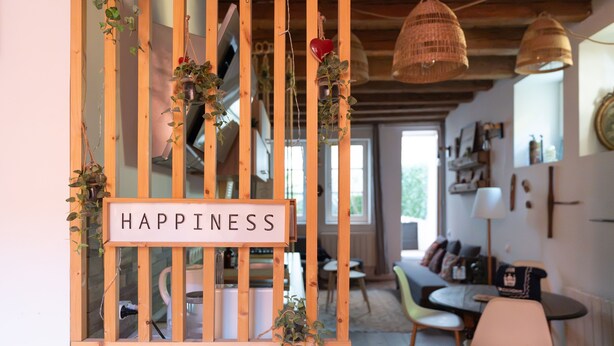 A wooden-framed window with a sign reading 'HAPPINESS,' a dining area with chairs and a table, and a kitchen in the background. - Le Patio - Ancien atelier de soyeux avec terrasse (Lyon)