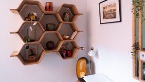 A hexagonal wooden shelf unit with various decorative items and a framed picture on the wall. - Le Patio - Ancien atelier de soyeux avec terrasse (Lyon)