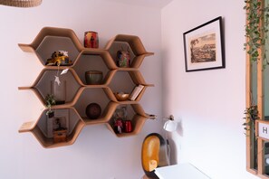 Ein sechseckiges Holzregal mit verschiedenen Dekorationsobjekten und einem gerahmten Bild an der Wand.