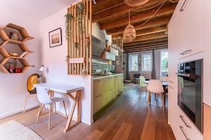 Une cuisine moderne avec des meubles en bois, un coin repas avec des chaises et une vue sur l’extérieur.