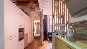 A modern kitchen with wooden flooring, white cabinets, and a hanging light fixture. - Le Patio - Ancien atelier de soyeux avec terrasse (Lyon)