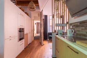 Eine moderne Küche mit Holzböden, weißen Schränken und einer Hängeleuchte.