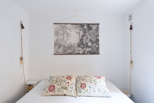 Une chambre à coucher avec un lit, deux lampes de chevet, un tableau accroché au mur et une table de chevet.