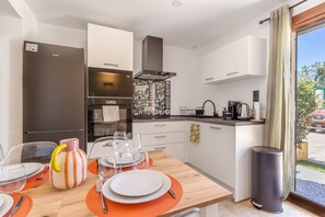 A modern kitchen with a dining area, featuring a refrigerator, stove, and various kitchen appliances. - L'Ecrin de Capitello - Bel appt proche plage (Grosseto-Prugna)