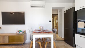 Une cuisine moderne avec un coin repas, un réfrigérateur noir et un téléviseur à écran plat fixé au mur.