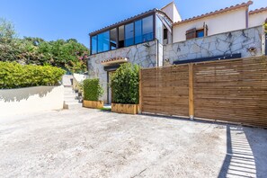 A modern house with a stone facade, a large wooden gate, and a clear sky. - L'Ecrin de Capitello - Bel appt proche plage (Grosseto-Prugna)