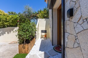 A stone building with a wooden planter and a grill outside. - L'Ecrin de Capitello - Bel appt proche plage (Grosseto-Prugna)