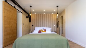 Une chambre moderne avec un grand lit, un mur revêtu de panneaux en bois et des luminaires suspendus.