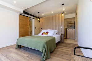 A modern bedroom with a bed, wooden panel wall, and a hanging light fixture. - L'Ecrin de Capitello - Bel appt proche plage (Grosseto-Prugna)