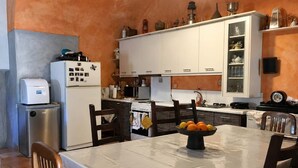 Una cocina con armarios blancos, una estufa y una mesa con un frutero.