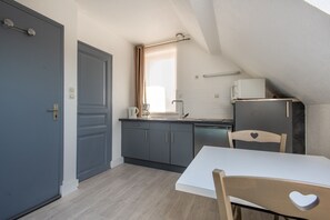 A compact kitchen with grey cabinets, a white countertop, and a small refrigerator. - Chez Alain - Proche plage du Touquet (Etaples-sur-Mer)