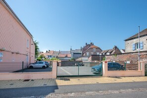 A residential area with a gated entrance, parked cars, and houses with visible chimneys and windows. - Chez Alain - Proche plage du Touquet (Etaples-sur-Mer)