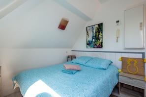A bedroom with a bed, a nightstand, a wall-mounted phone, and a painting of the Eiffel Tower. - Chez Alain - Proche plage du Touquet (Etaples-sur-Mer)