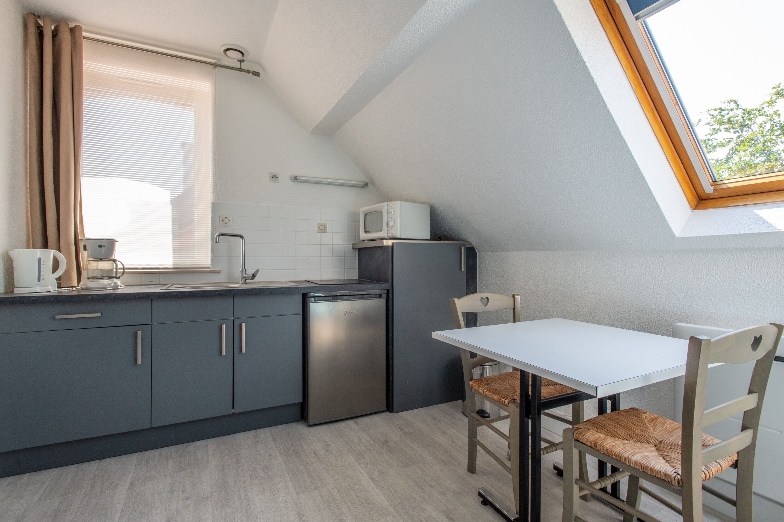 A compact kitchen with a built-in dishwasher, a microwave, and a dining area with a table and chairs.