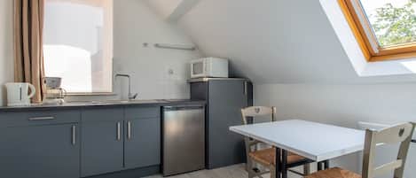 A compact kitchen with a built-in dishwasher, a microwave, and a dining area with a table and chairs.