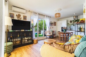 A living room with a TV, sofa, and dining area. - Azur & Magnolia - À 750 m de la plage (La Seyne-sur-Mer)