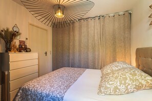 A bedroom with a bed, a dresser, a mirror, and a hanging light fixture. - Azur & Magnolia - À 750 m de la plage (La Seyne-sur-Mer)
