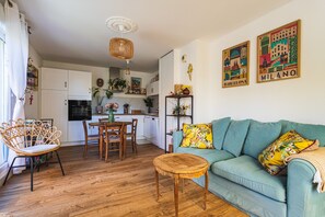 A living room with a sofa, a coffee table, and a dining area with chairs and a table. - Azur & Magnolia - À 750 m de la plage (La Seyne-sur-Mer)