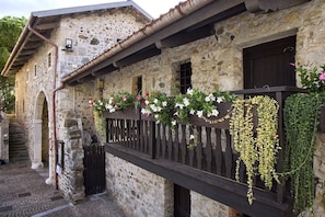 A stone building with a wooden balcony, a metal gate, and a staircase leading to an upper level.