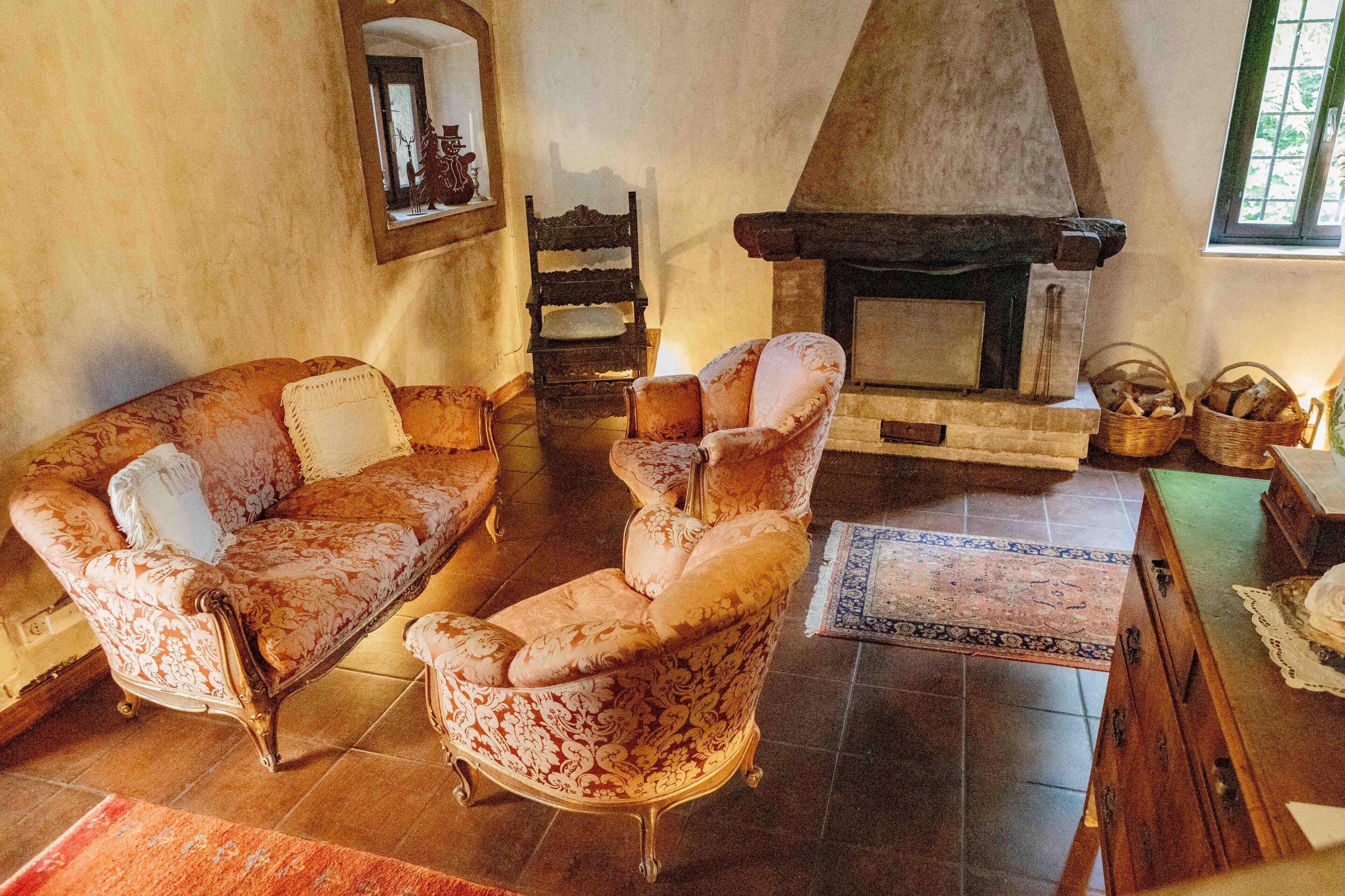 Ein traditionell eingerichtetes Wohnzimmer mit Kamin, einer Couch, einem Sessel und einem Tisch mit Körben.