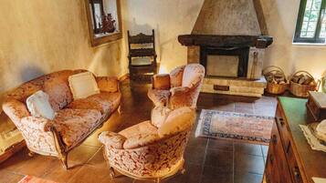 Ein traditionell eingerichtetes Wohnzimmer mit Kamin, einer Couch, einem Sessel und einem Tisch mit Körben.