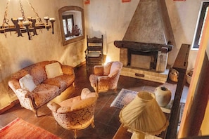 A traditional living room with a fireplace, patterned sofas, and a hanging light fixture.