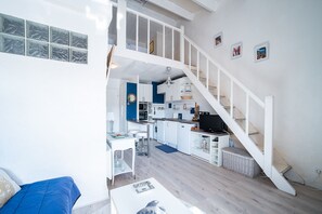 A compact living space with a kitchen, dining area, and a staircase leading to an upper level. - L'Écrin Bleu - À 300 m de la plage (Argeles-sur-Mer)
