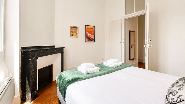 A bedroom with a bed, a fireplace, two posters on the wall, and a door leading to another room. - Confidence - À 400 m du métro Jeanne d'Arc (Toulouse)