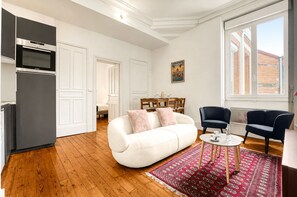 A modern living room with a sofa, chairs, a dining table, and a kitchen area. - Confidence - À 400 m du métro Jeanne d'Arc (Toulouse)