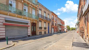 A street with buildings, closed shop fronts, and a clear sky. - Confidence - À 400 m du métro Jeanne d'Arc (Toulouse)