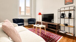 A modern living room with a sofa, chairs, a coffee table, a TV, and a bookshelf. - Confidence - À 400 m du métro Jeanne d'Arc (Toulouse)