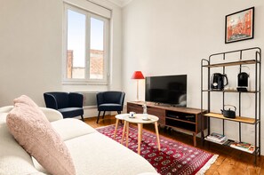 Ett modernt vardagsrum med en soffa, fåtöljer, ett soffbord, en tv och en bokhylla.
