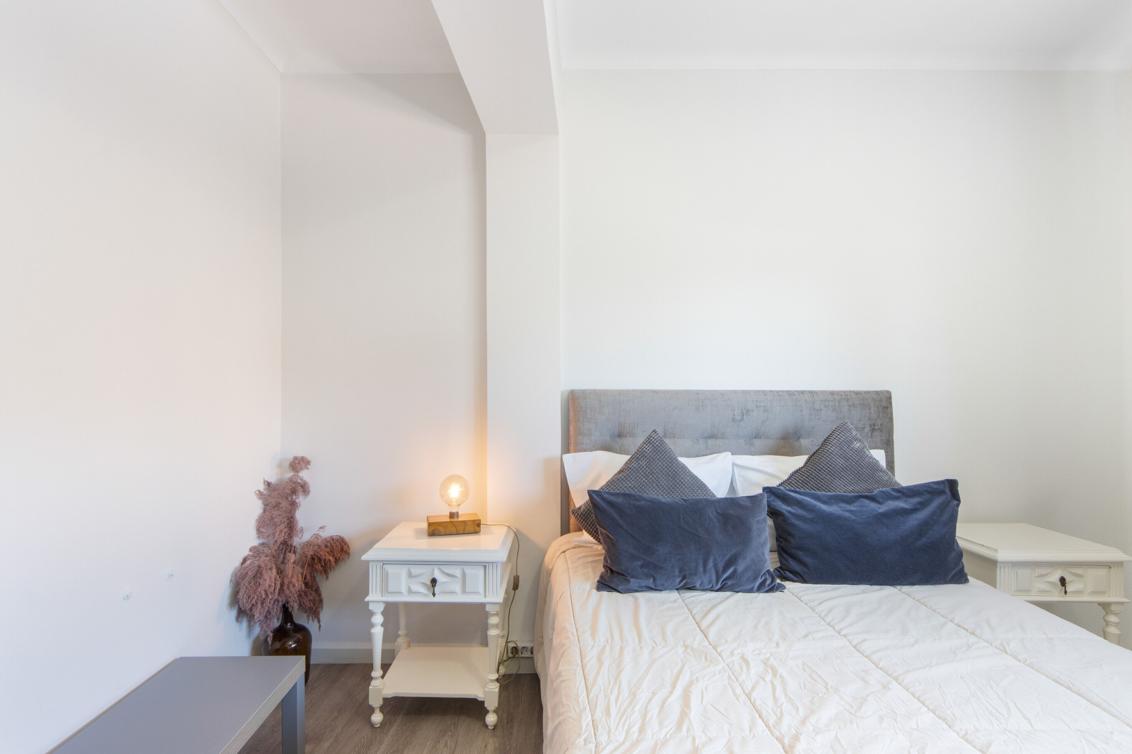 A bedroom with a bed, bedside tables, a nightstand, and a lamp.
