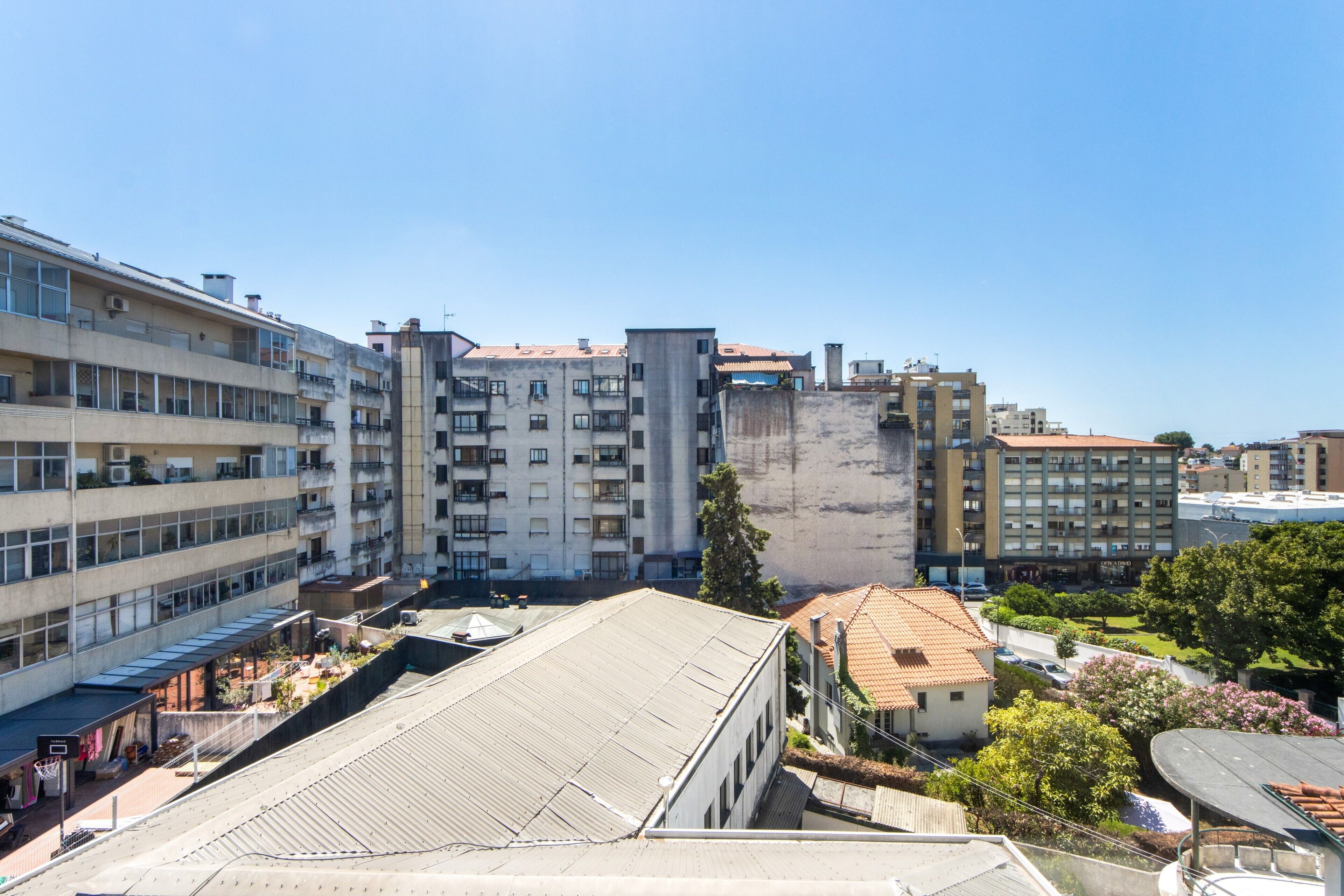 A multi-story building with a flat roof, large windows, and a courtyard with a basketball court.