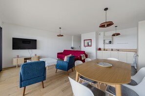 Ein modernes Wohnzimmer mit Esstisch, einem roten Sofa und einem an der Wand befestigten Fernseher.