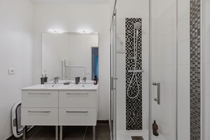 Ein modernes Badezimmer mit einem weißen Waschtisch, einer Duschkabine aus Glas und einer backsplash aus Schachbrettfliesen.
