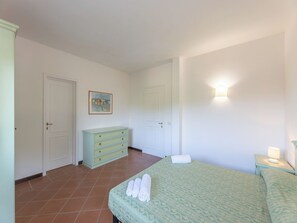 A bedroom with a bed, a dresser, a painting, and a nightstand with a lamp. - Comfortable and Bright Apartment (Stintino)