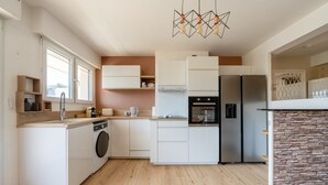 A modern kitchen with a built-in washing machine, a stove, and a refrigerator. - L'Alma du Laudon - Centre village et climatisation (Saint-Jorioz)