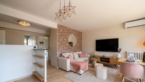 A modern living room with a sofa, coffee table, and TV. - L'Alma du Laudon - Centre village et climatisation (Saint-Jorioz)
