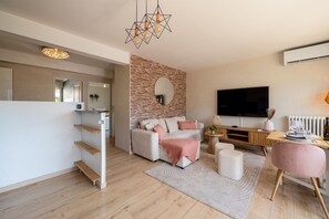 A modern living room with a sofa, coffee table, and TV. - L'Alma du Laudon - Centre village et climatisation (Saint-Jorioz)
