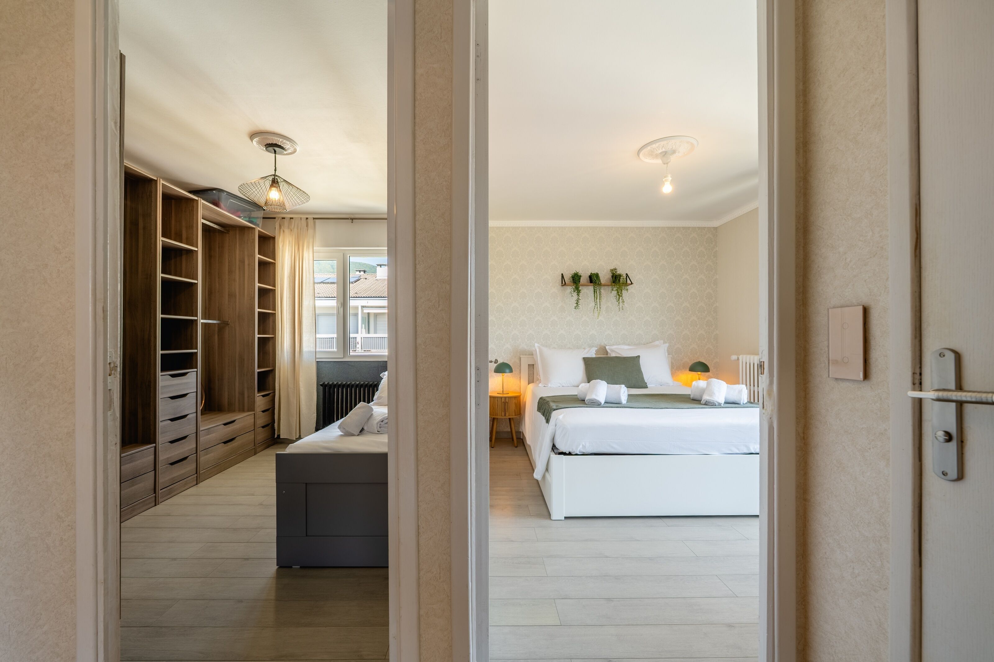 Une chambre à coucher avec un lit, une table de chevet, une lampe et une vue sur l’extérieur.